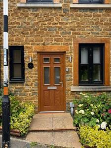 a brick house with a wooden door and two windows at Church Court 2 Bed 55 Inch SKY TV Northampton Parking Contractor Accommodation in Earls Barton