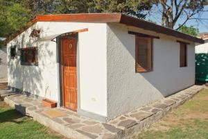 a small white building with a wooden door at Cabañas LA BUENA FE in La Falda