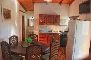 a kitchen with a table and a white refrigerator at Cabañas LA BUENA FE in La Falda