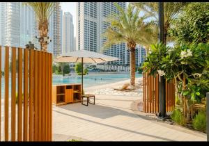 a table with an umbrella next to a pool with buildings at Exquisite 1-Bedroom with Pool Scenery in Dubai Creek Harbour in Dubai