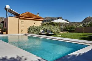 a swimming pool with two chairs and an umbrella at Mouri Villa in Mouríon
