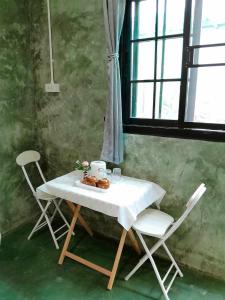 a table with two chairs and a table with food on it at บ้านอังกาบ Aungkab homestay in Ban Muang Len +26 photos