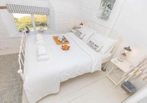 a white bedroom with a white bed and a window at Coast Barn, Noss Mayo, Plymouth in Plymouth