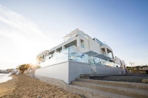 una casa bianca sulla spiaggia con scale di Scirocco Boutique Eco Hotel a Torre Pali