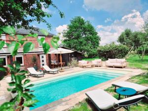 basen z krzesłami i stołami obok domu w obiekcie Jacuzzi, Piscine, Station de recharge pour véhicule électrique, Maison normande du 19ème Siècle à 25' de Deauville, classée meublé de tourisme 5 étoiles w mieście Saint-Philbert-des-Champs