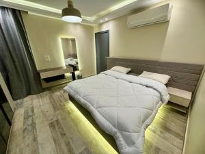 ein Schlafzimmer mit einem großen weißen Bett und einem Spiegel in der Unterkunft Charming Luxury Apartment - New Cairo in Kairo