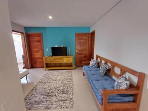 Una sala de estar con un sofá azul y un televisor en Apartamento em Arraial, en Arraial d'Ajuda