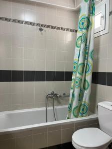 a bathroom with a tub and a toilet and a shower curtain at Aspasia Apartment in Kanali +14 photos