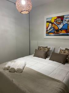 un grande letto bianco in una stanza con un dipinto di Apartamento Praia Porto mais Alegre a Porto Seguro