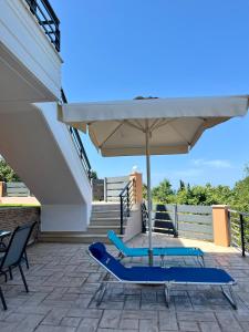 a patio with an umbrella and two chairs and a table at Aspasia Apartment in Kanali