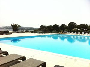 a large swimming pool with blue water and chairs at Villa Pieds dans l eau in Porto-Vecchio