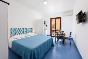 a bedroom with a bed and a table and a television at Paradiso Holiday Home in San Vito lo Capo
