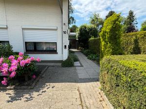 a house with a driveway and flowers in front of it at Birkenweg Ankerplatz II in Carolinensiel