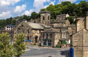 an old stone building with a clock tower on a hill at Lane End Cottage Holmfirth - Panoramic Views, Modernised with offroad parking in Holmfirth