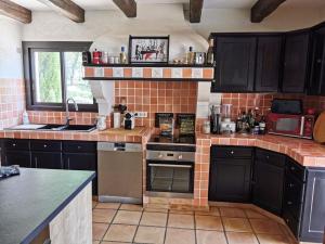 une cuisine avec des armoires noires et un mur en briques dans l'établissement Villa de charme entre mer et montagne, à Mons