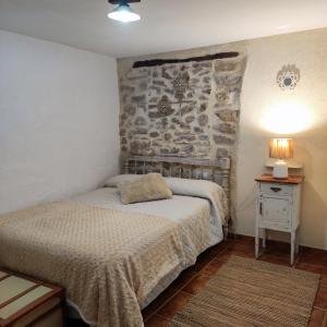 una camera da letto con un letto e un muro di pietra di Alcoba con patio del siglo XIX a Villanueva de Viver