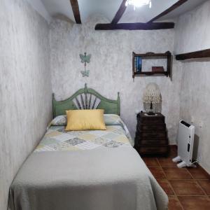 una camera da letto con un letto con un cuscino giallo sopra di Alcoba con patio del siglo XIX a Villanueva de Viver Altre 12 foto