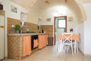 a kitchen with an archway and a table and chairs at trullo madonna della grotta in Ceglie Messapica