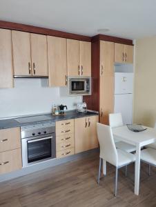 una cucina con armadi in legno, tavolo e forno a microonde di Apartamento Barranquilla a Poyales del Hoyo