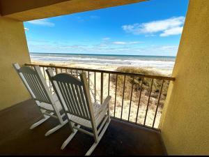 2 Stühle auf einem Balkon mit Strandblick in der Unterkunft Surf Side Hotel in Nags Head