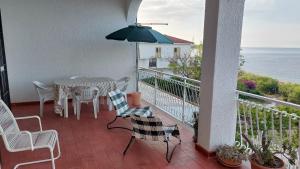 a balcony with a table and chairs and an umbrella at Corallo Blu Appartamento sul mare in Riaci Capo
