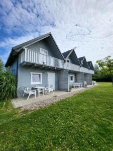 a house with tables and chairs in front of it at Domki Letniskowe Gris in Grzybowo