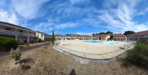 a building with a large pool in a courtyard at Appartement Le Verdon sur mer in Le Verdon-sur-Mer