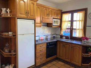 a kitchen with wooden cabinets and a white refrigerator at El Corral in Llanes