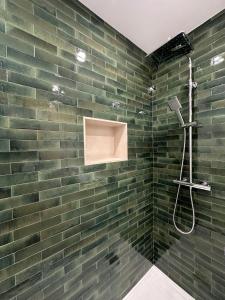 a bathroom with a green brick wall and a shower at Aire de Picos Norte in Brez