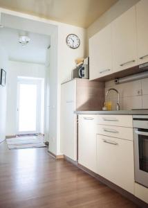 a kitchen with white cabinets and a clock on the wall at Spacious cozy home and sunny terrace in Nida in Neringa