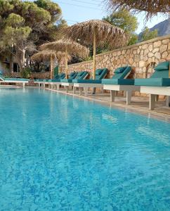 a swimming pool with blue chairs in a resort at Ifestia Hotel in Kamari
