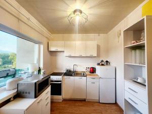 a small kitchen with white cabinets and a window at Viscosa külaliskorter in Kõrgessaare