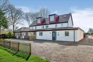 ein großes weißes Haus mit einem Zaun davor in der Unterkunft 1 Orchard Farm Cottages Sleeps 10, Open plan Kitchen & Large Garden in East Grinstead