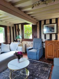 クウェットヴィルにあるLa longère dans la prairieのソファとテーブルのあるリビングルーム