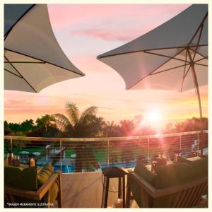 un patio con sedie e ombrellone su un balcone di Apartamento 10min da praia a pé rota turística a Parnamirim