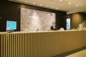 a woman is standing behind a counter in a room at Jinjiang Inn Dalian Lianhe Road in Dalian