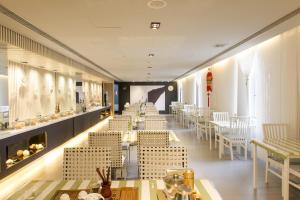 a restaurant with white chairs and tables and a row of tables at Jinjiang Inn Dalian Lianhe Road in Dalian