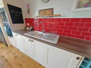 a kitchen with a sink and red tiles on the wall at Avro in Southampton +31 photos