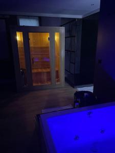 a dark room with a window and a desk with a monitor at Le Cocon des Granges - Suite Sauna Jaccuzi SPA in Bonnières-sur-Seine