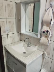 a bathroom with a white sink and a mirror at APARTAMENTO SIMPLES E ACONCHEGANTE in Paraty