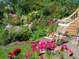 a wooden bench sitting in a garden with flowers at Landhaus Wildfeuer in Kirchdorf im Wald