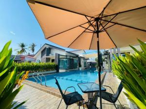 a table with an umbrella next to a swimming pool at Tijami Villa & Resort in Kampong Mangkok