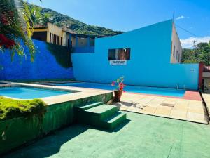 a blue house with a swimming pool and a church at Complexo Turístico Gruta da Serra in Guaramiranga