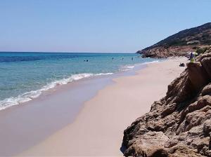 ein Sandstrand mit Menschen, die im Meer schwimmen in der Unterkunft Apartment in Santa Margherita di Pula 48219 in Santa Margherita di Pula