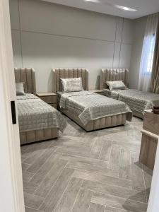 three beds in a room with wooden floors at فيلا عطر الهدا in Al Hada