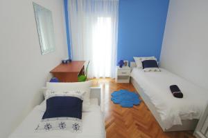 a room with two beds and a desk and a window at Guest House Renata in Zadar
