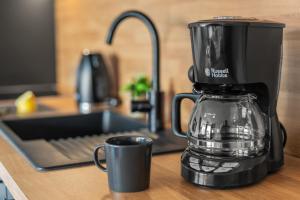 una macchinetta del caffè seduta su un bancone accanto a una tazza di BLICKFANG - zentrale Ferienwohnung im Herzen von Friedrichshafen a Friedrichshafen