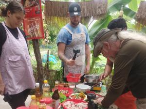 een groep mensen die rond een tafel met eten staan bij Phonluer Angkor Homestay, in Siem Reap