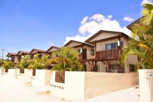 a row of houses on the beach with palm trees at Churaumi Village in Motobu