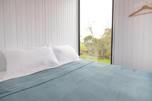 a bedroom with a bed with a large window at McCabe Farm Cabin by Tiny Away in Brookton